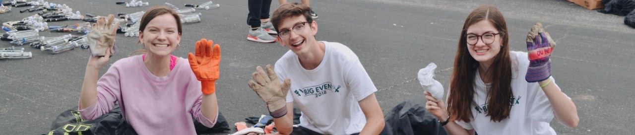 Three students hold up their gloved hands while volunteering at the 2018 Big Event.