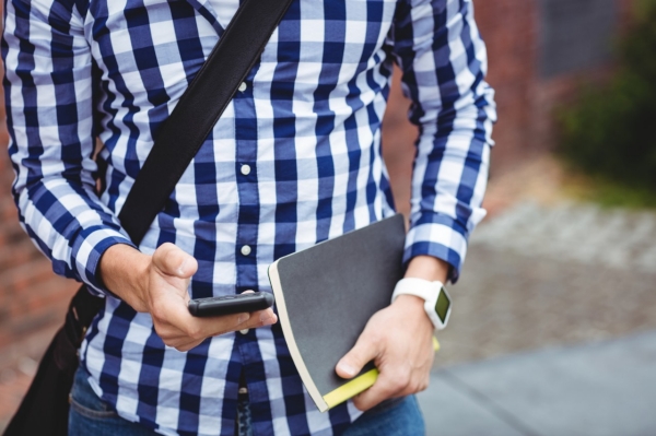 Mid section of student using mobile phone in college campus