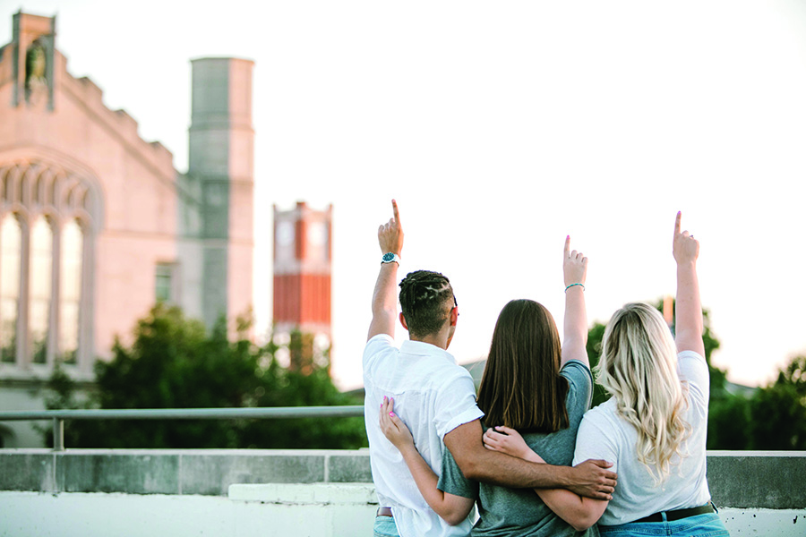 three students pointing at the sky