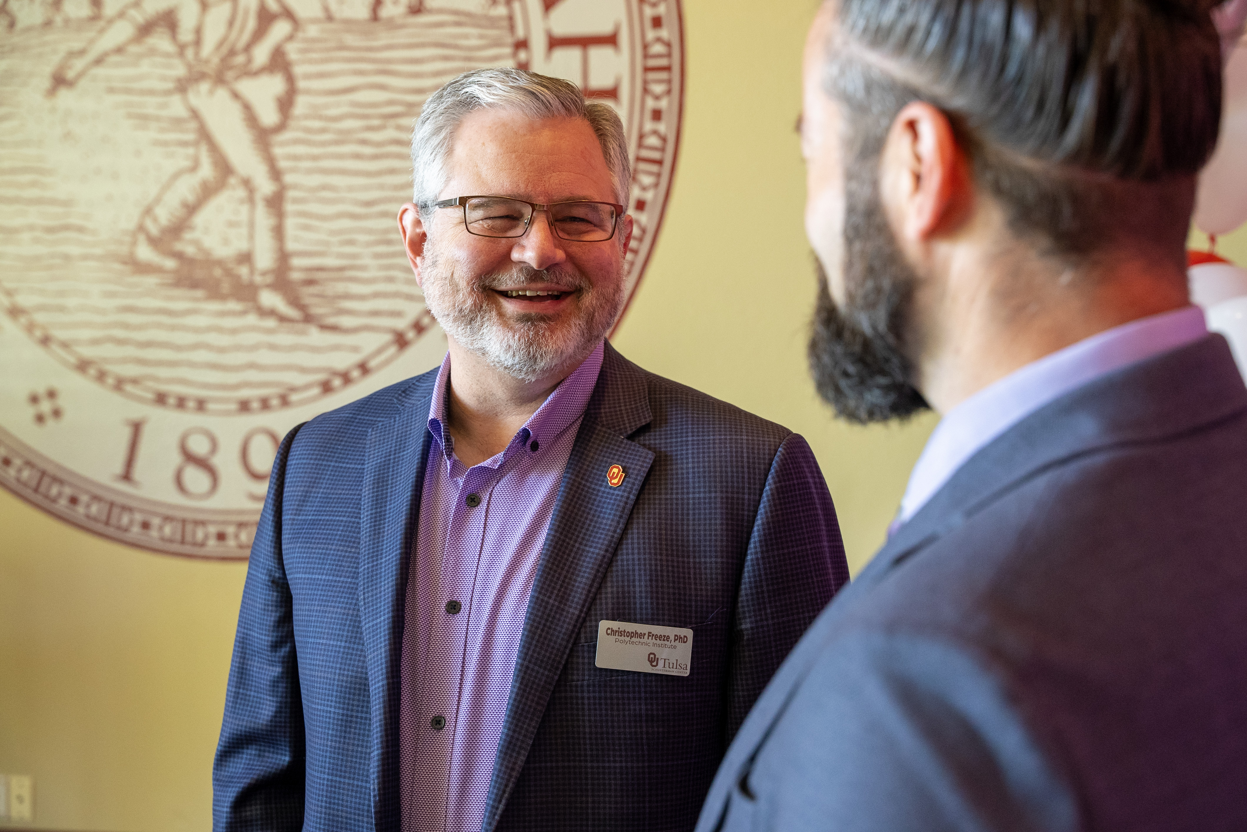 Dr. Chris Freeze chatting in front of the OU seal