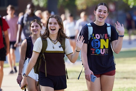 Two students waving hello on campus