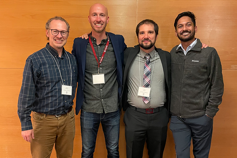 Four men standing together smiling