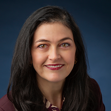 Woman with dark hair and smiling in a dark blazer