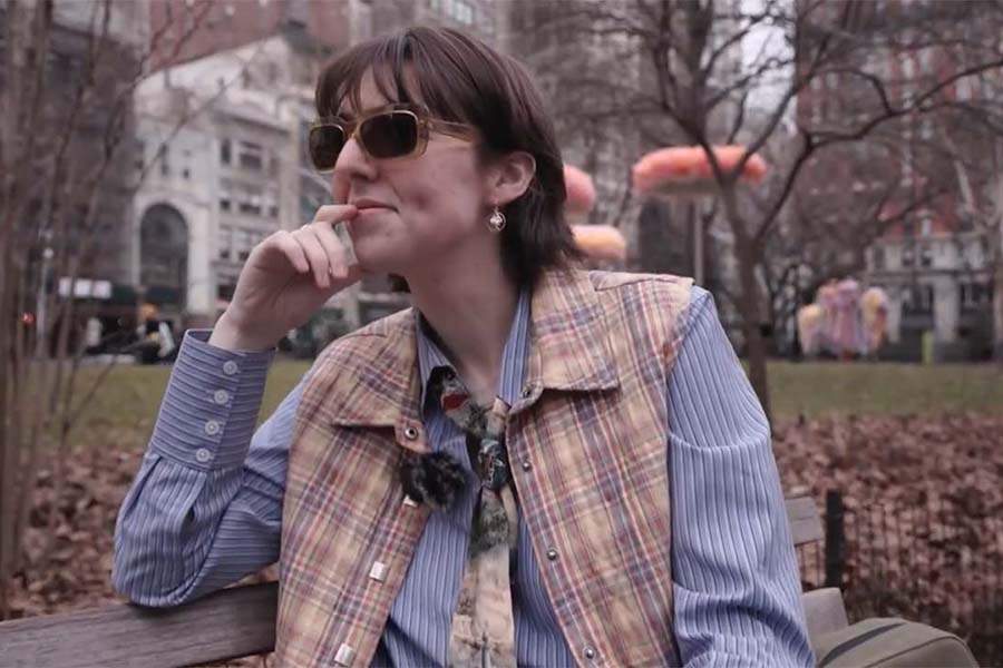 Georgia Bomar sitting on a bench in NYC looking off into the distance.