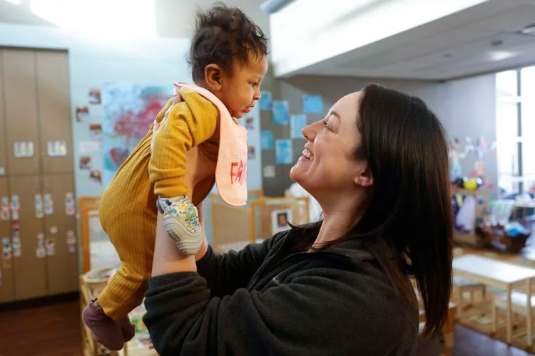 Teacher Brooke Mikish holds 3-month-old Ariyah Simon after the baby woke up from her nap at the MacArthur Tulsa Educare