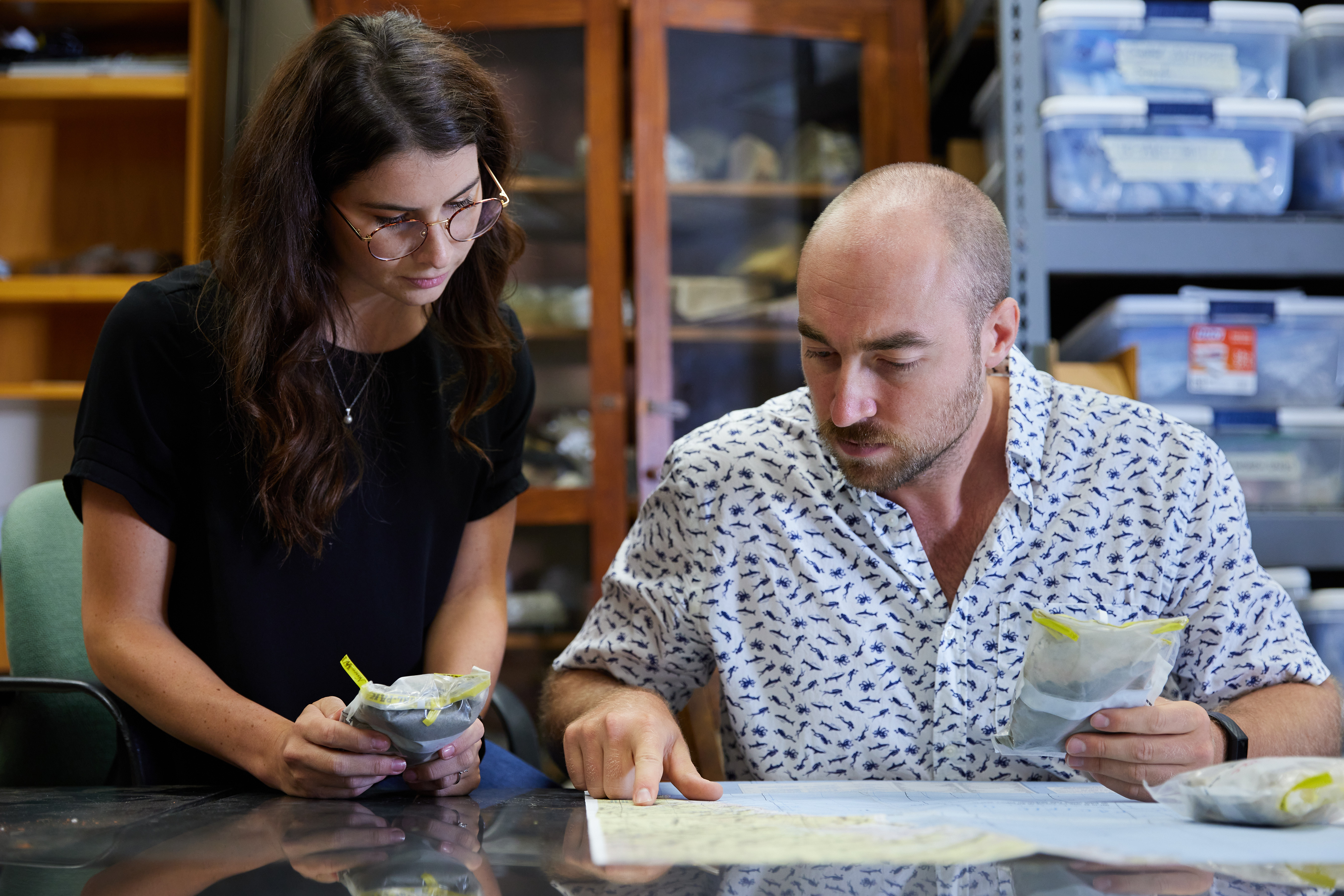 Students in a lab analyzing rock samples and a map.