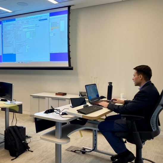 Researcher in front of classroom at a computer teaching software.