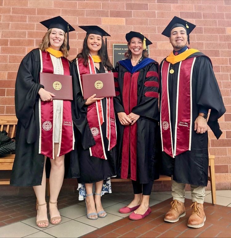 Students in graduation gowns holding diplomas.