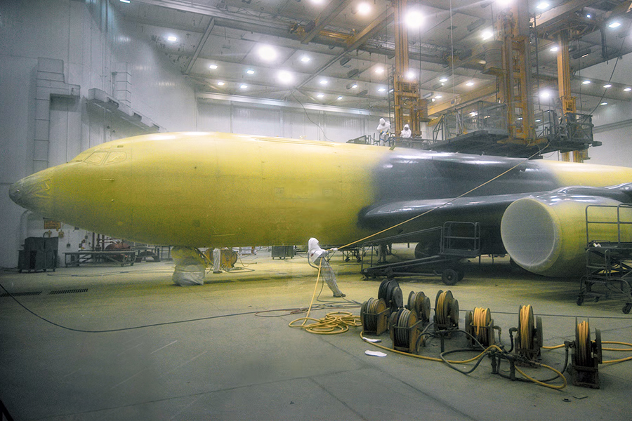 A military plane being painted with yellow primer.