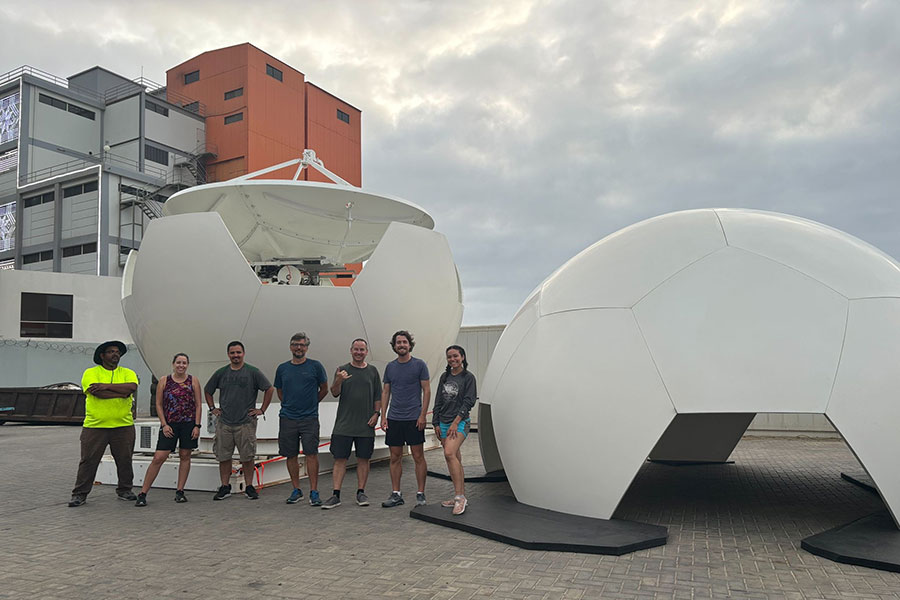 A group of scientists stands in front of a near-completed radar.