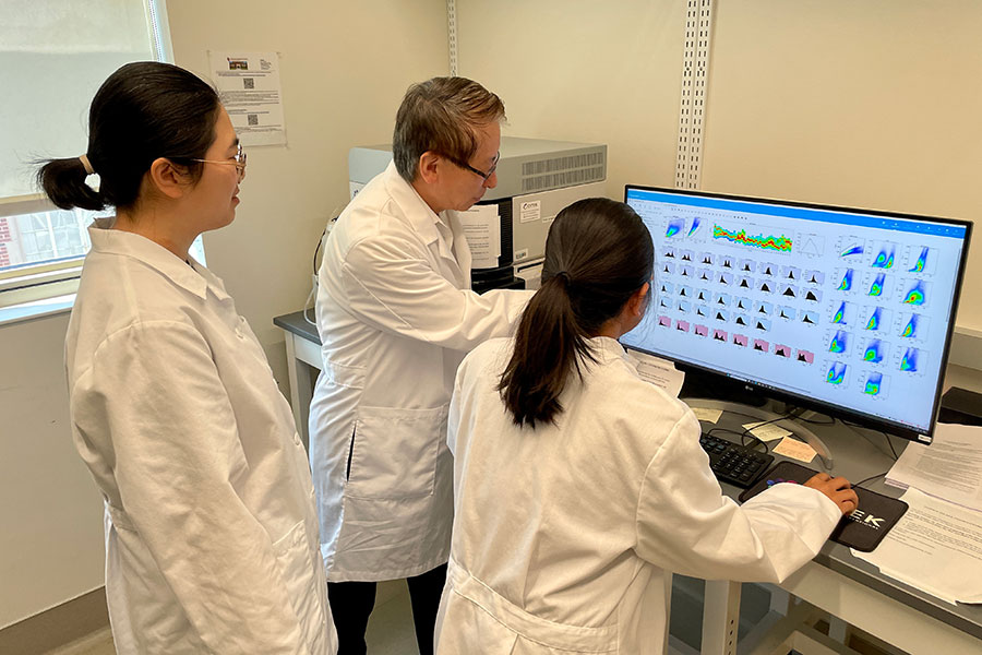 A team of three scientists examining data on a computer.