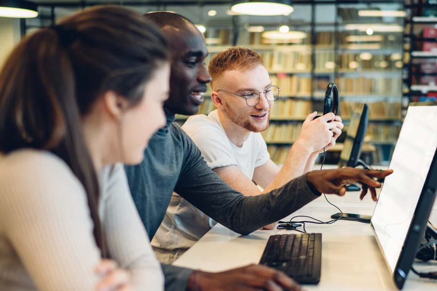 Three people collaborating together around a computer monitor.