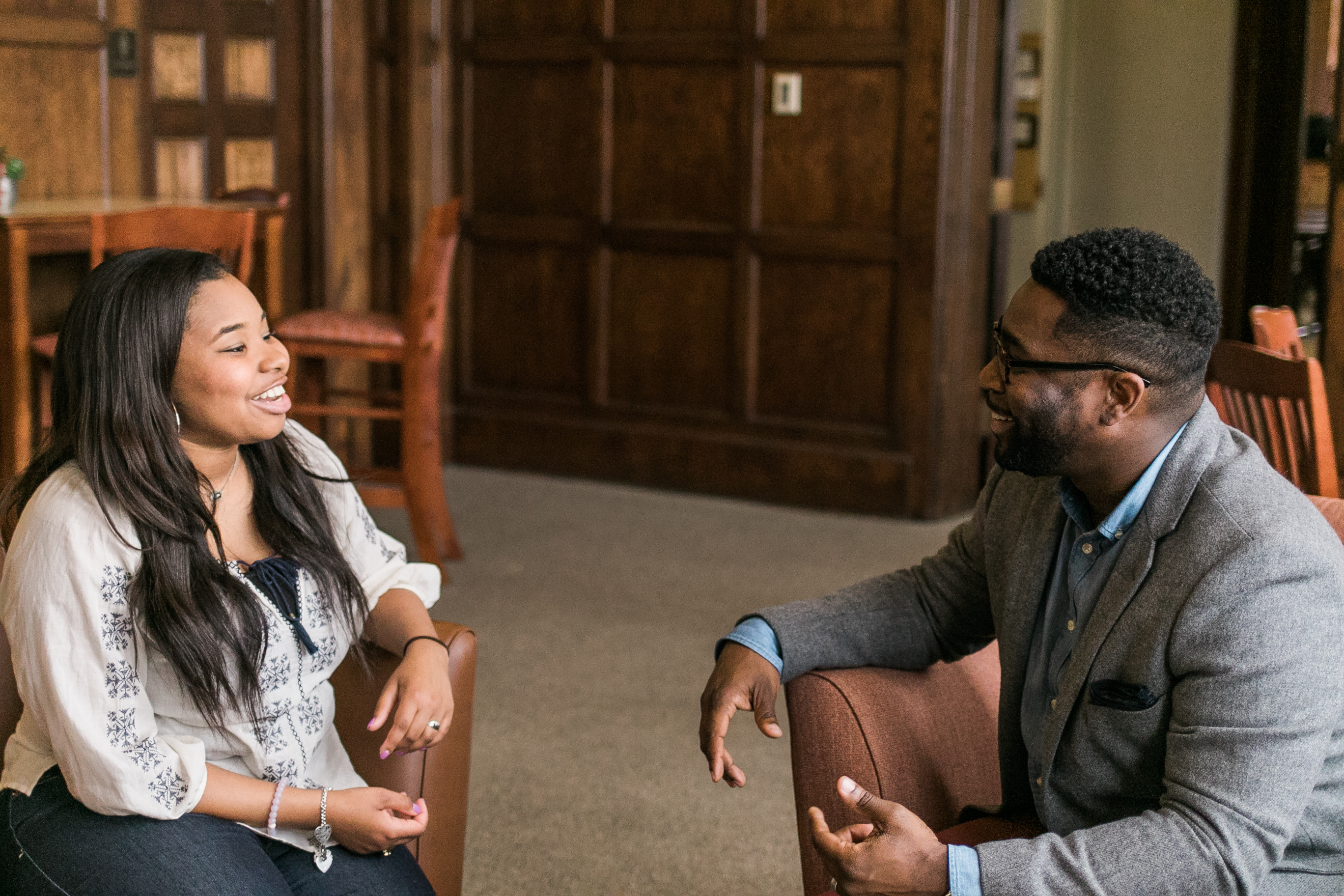 Two people sitting across from each other talking and smiling