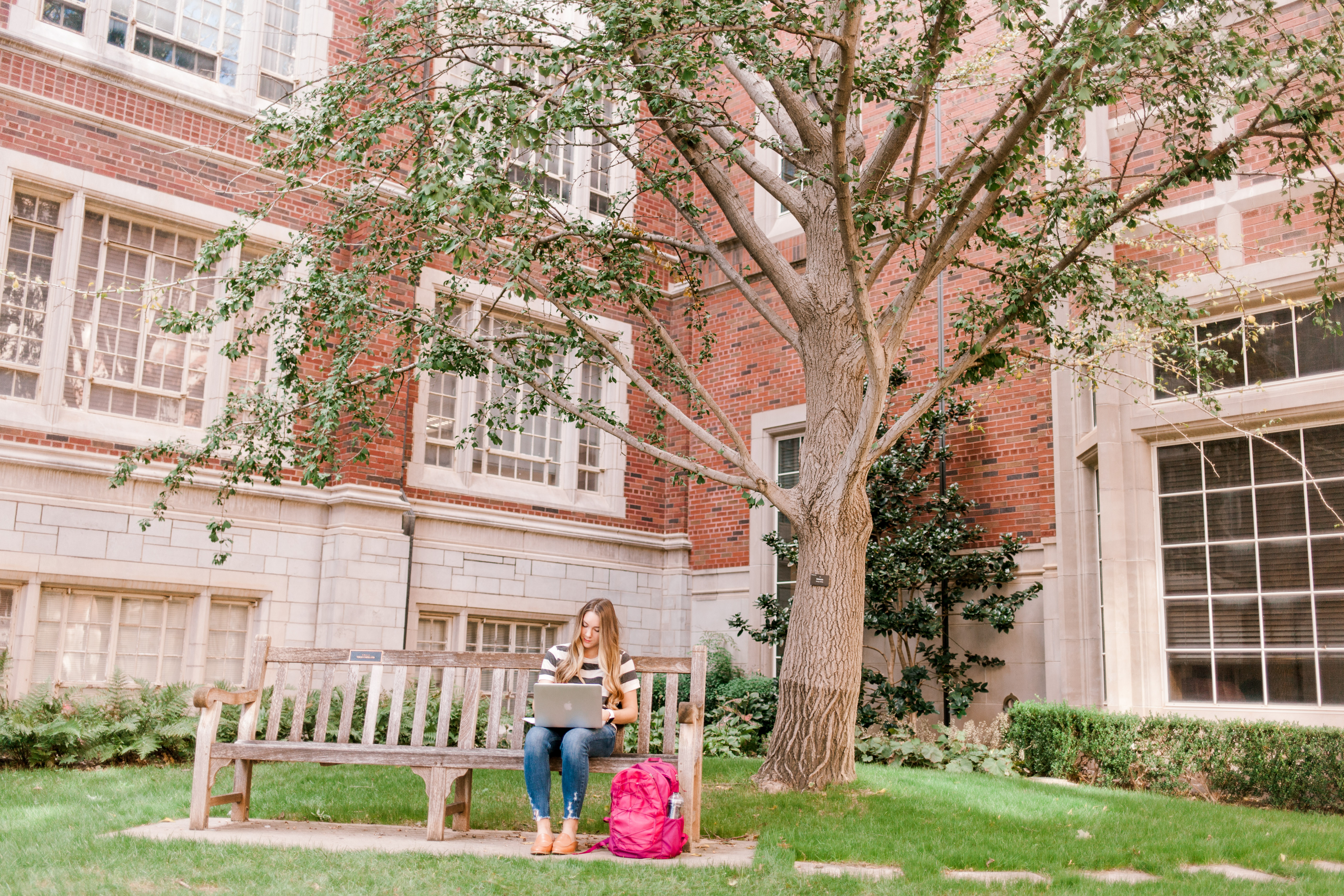 Student sitting outside Adams Hall working on computer