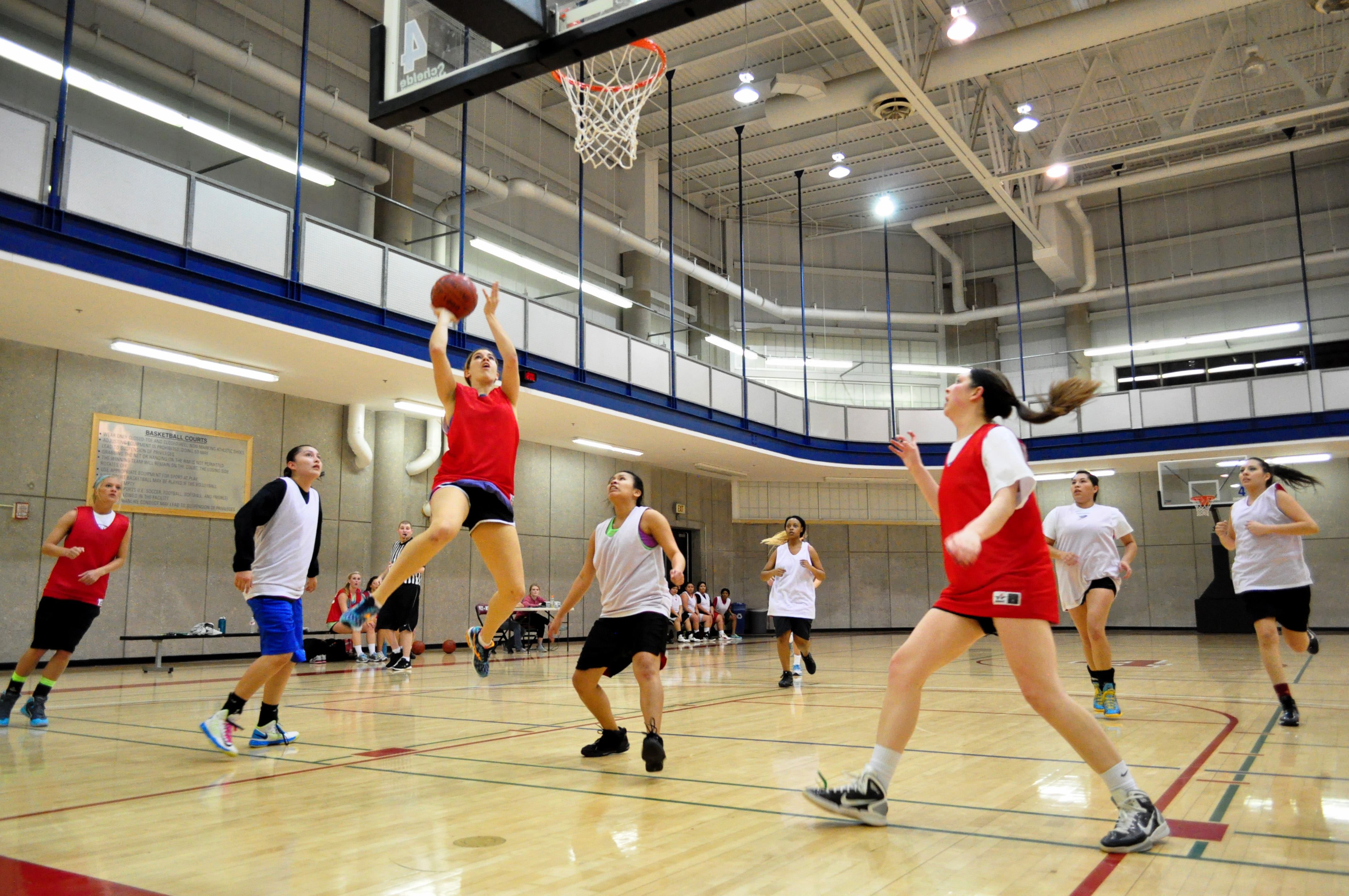 Students playing basketball indoors.