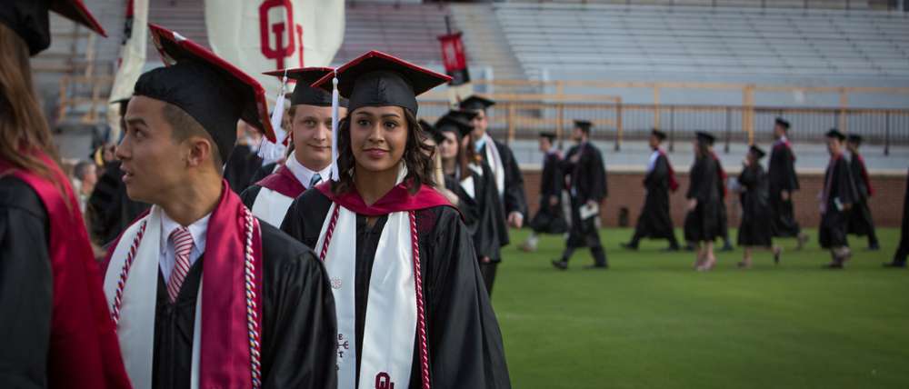 photo of graduates walking across football field at Commencement