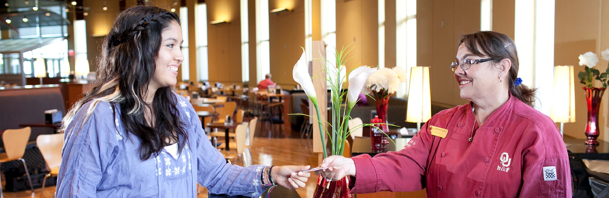 Student hands her Sooner Card to a Food Services employee in Couch Restaurants