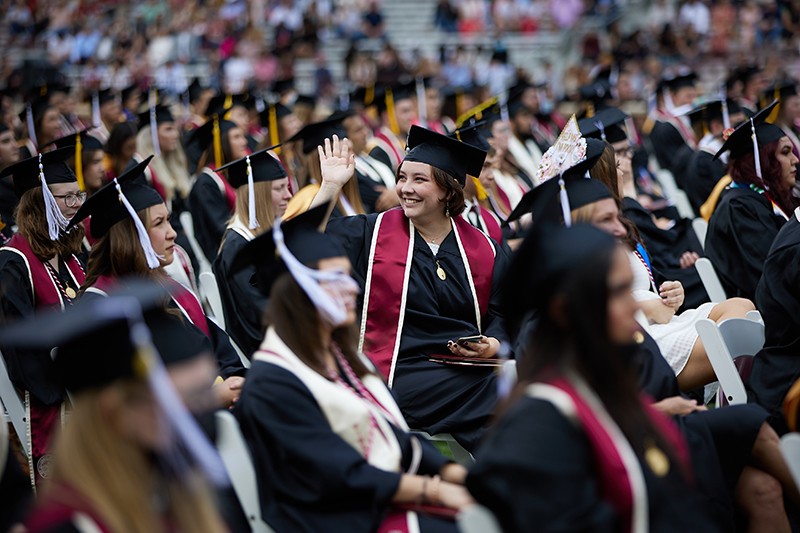 Student waves from seat during a LNC graduation ceremony