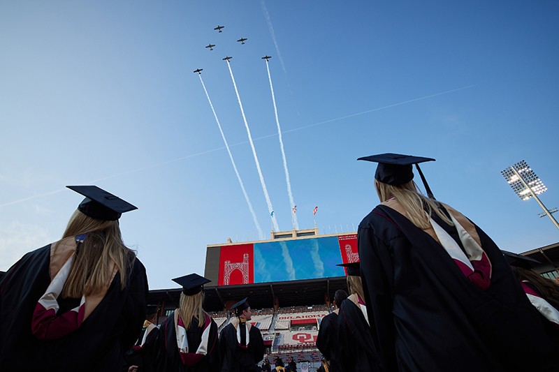 Students watch the warbirds plane flyover from the stadium