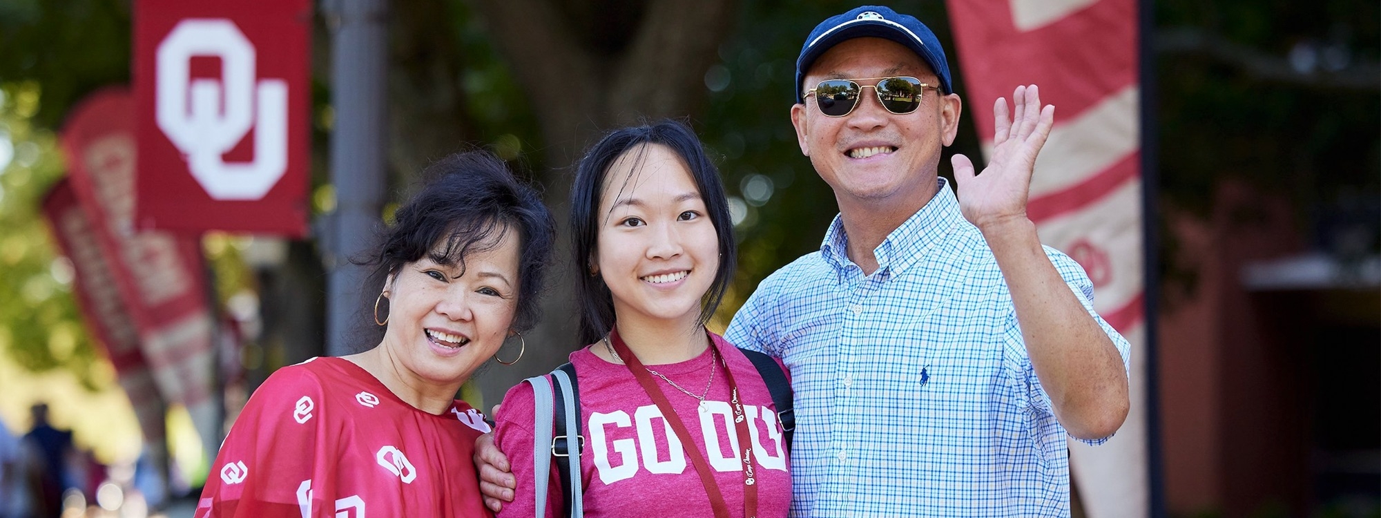 Two parents smile and wave at the camera during new student check-in