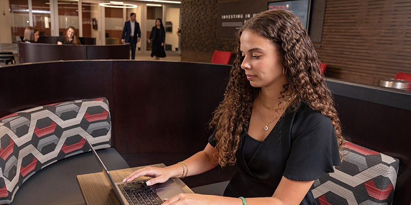 Female student sitting in a booth working on a laptop