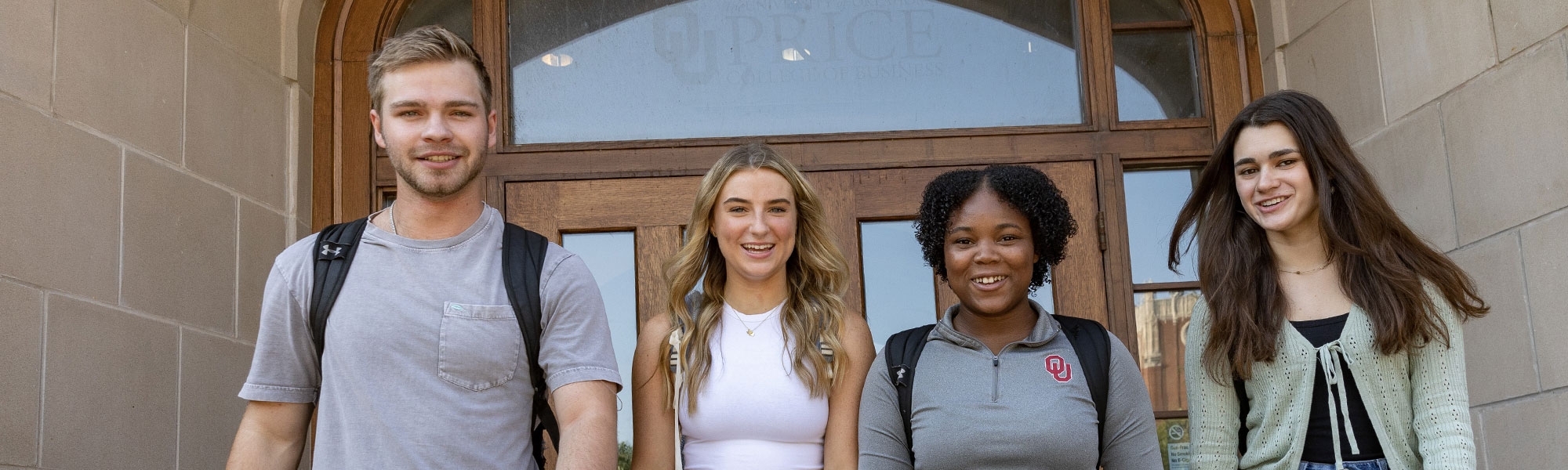 Four students walking out of an entrance of Price Hall.