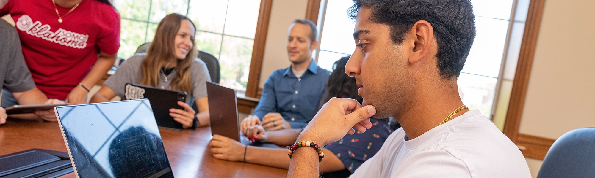 A student working on a laptop with other students nearby.