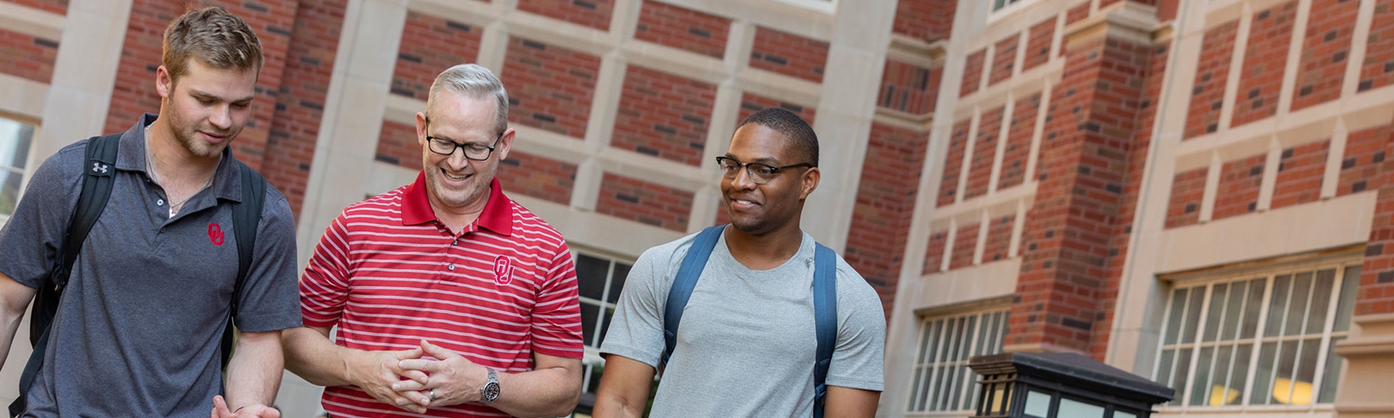 Dean Corey Phelps walking with two students through Dodson Courtyard with two students. 