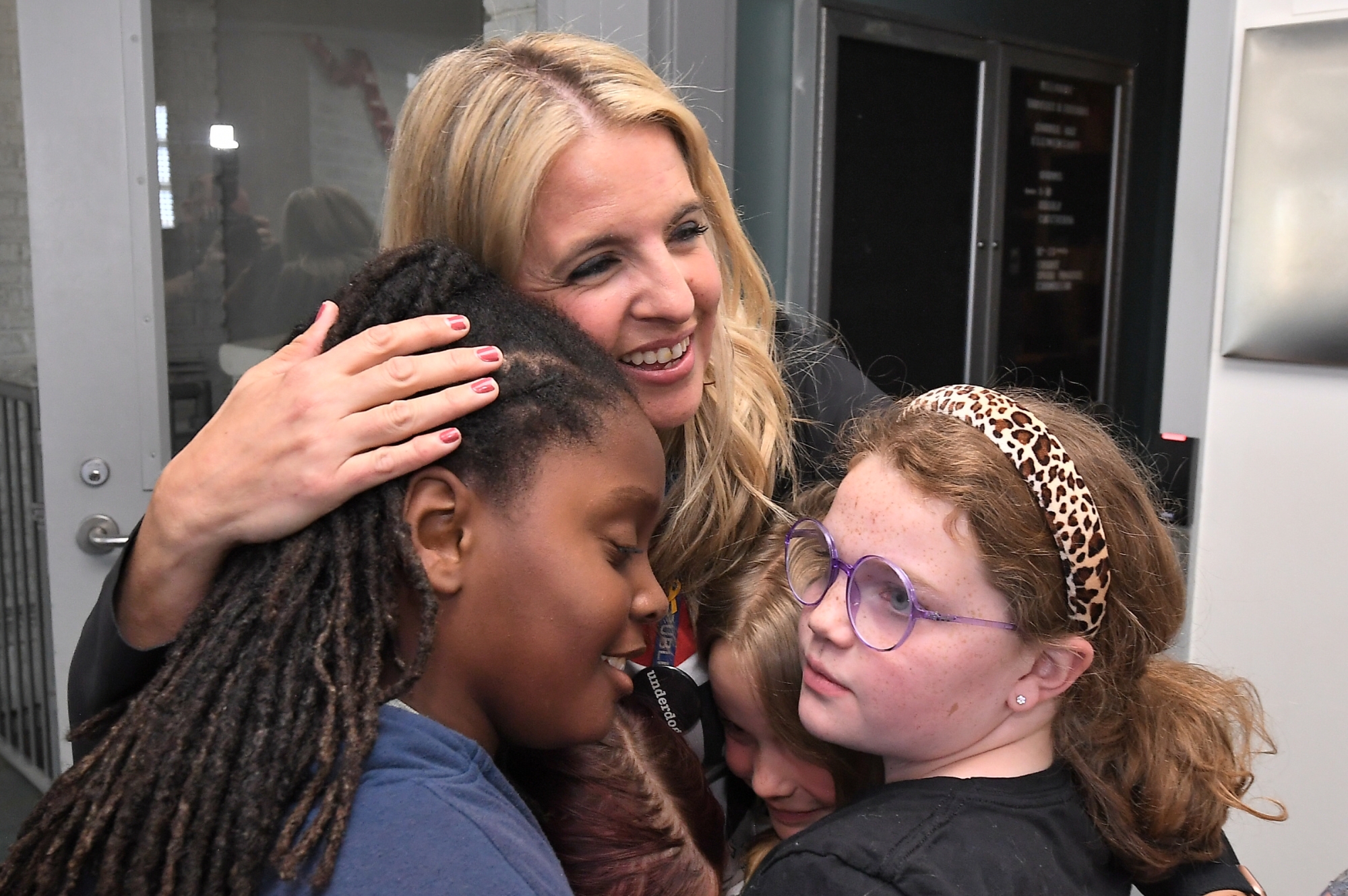 Aubrey Flowers hugging three students